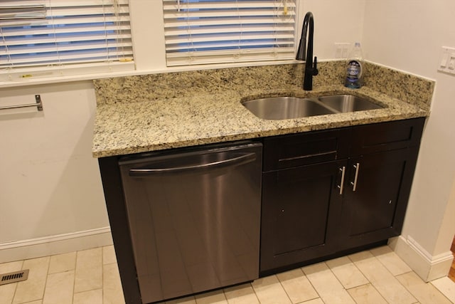 kitchen featuring dishwasher, light stone countertops, and sink