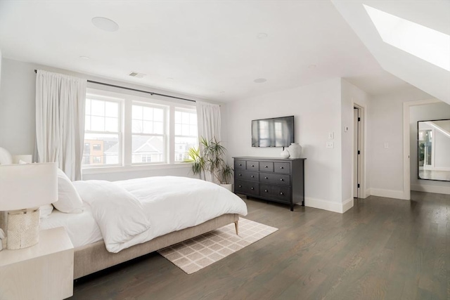 bedroom with a skylight and dark hardwood / wood-style flooring