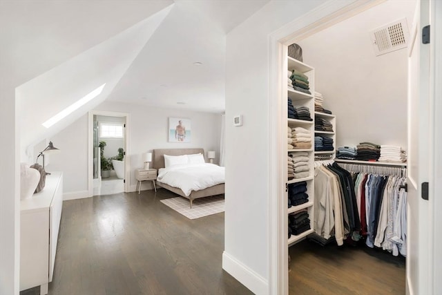 bedroom with dark hardwood / wood-style floors and lofted ceiling with skylight