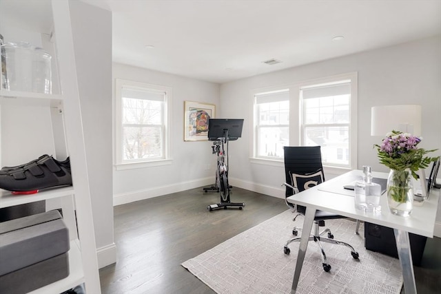 home office with a wealth of natural light and dark hardwood / wood-style floors