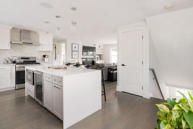 kitchen with stainless steel range oven, wall chimney range hood, white cabinetry, and pendant lighting