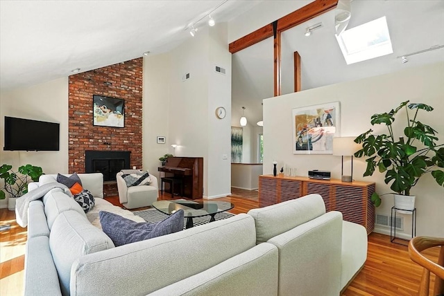 13 Robinwood Rd, Acton, MA 01720 - living area with a skylight, rail lighting, wood finished floors, a brick fireplace, and high vaulted ceiling