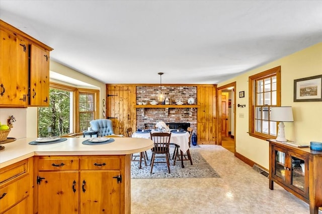 3 Five Cors, Barnstable, MA 02632 - kitchen featuring a brick fireplace, light countertops, a peninsula, and decorative light fixtures