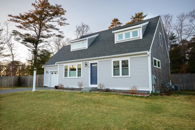 view of front of property with central air condition unit, a front lawn, aphalt driveway, an attached garage, and fence