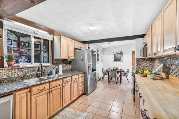 kitchen featuring light tile patterned floors, stainless steel appliances, backsplash, and a sink