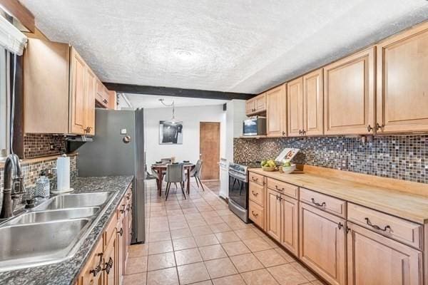 kitchen with stainless steel appliances, light brown cabinetry, backsplash, and a sink