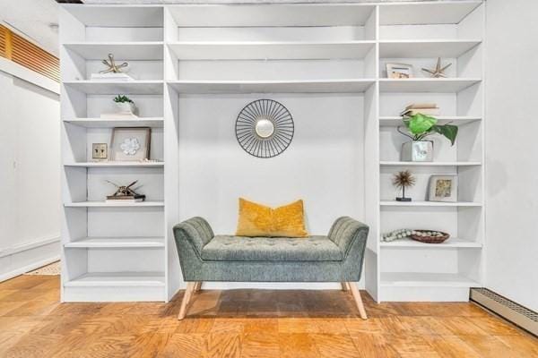 sitting room featuring a baseboard heating unit and built in shelves