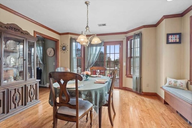 dining area with an inviting chandelier, ornamental molding, and light hardwood / wood-style flooring