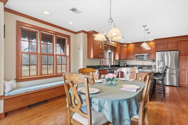 dining room featuring sink, wood-type flooring, and crown molding