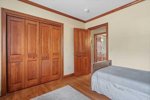 bedroom with light wood-type flooring, a closet, and crown molding