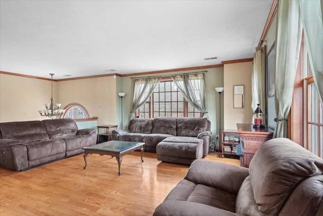 living room featuring light wood-type flooring, ornamental molding, and an inviting chandelier