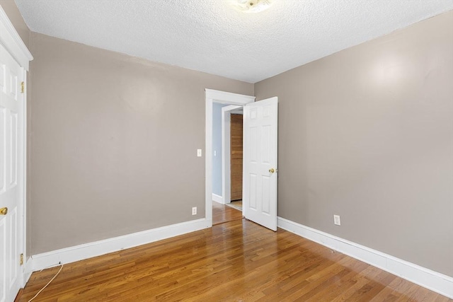 unfurnished room featuring hardwood / wood-style flooring and a textured ceiling