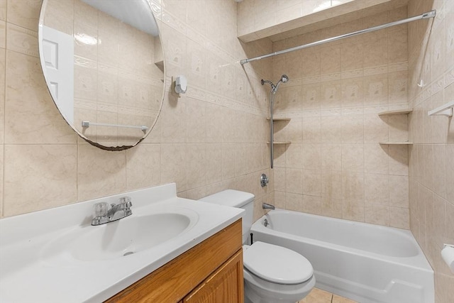 full bathroom with tile patterned floors, vanity, tiled shower / bath combo, tile walls, and toilet