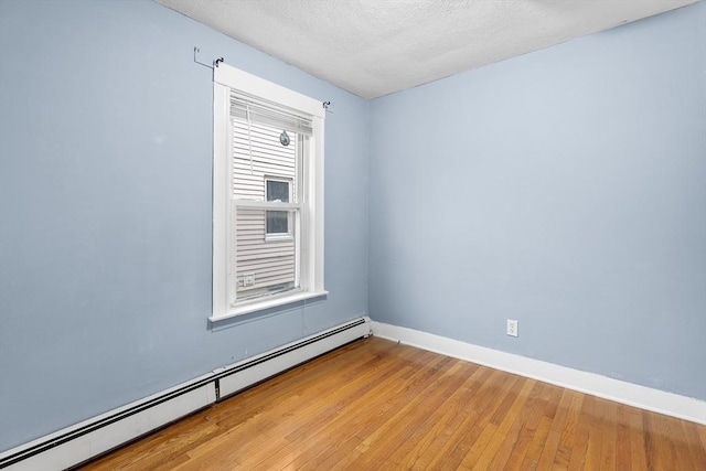 empty room featuring a textured ceiling, light hardwood / wood-style floors, and baseboard heating