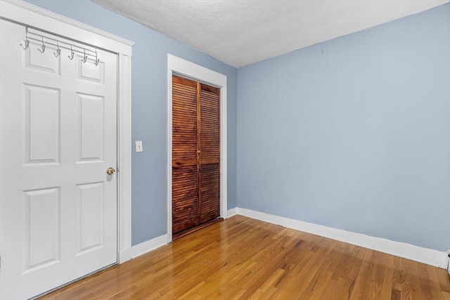 unfurnished bedroom with a closet, a textured ceiling, and light wood-type flooring