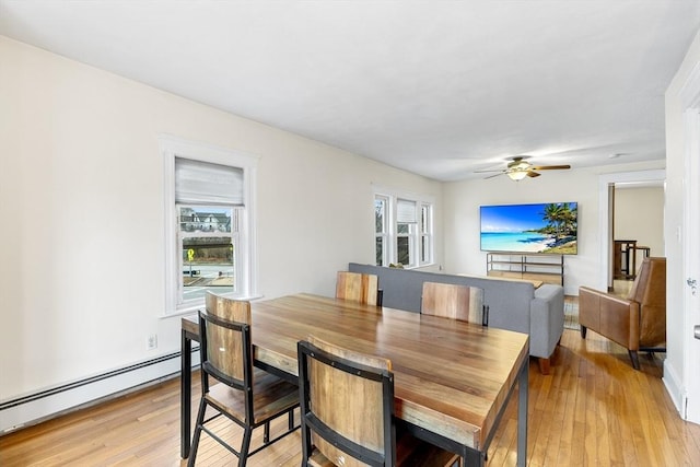 dining space with ceiling fan, light wood-type flooring, and a baseboard heating unit