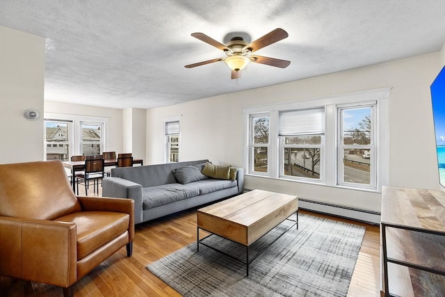 living room with ceiling fan, light wood-type flooring, a textured ceiling, and a baseboard radiator