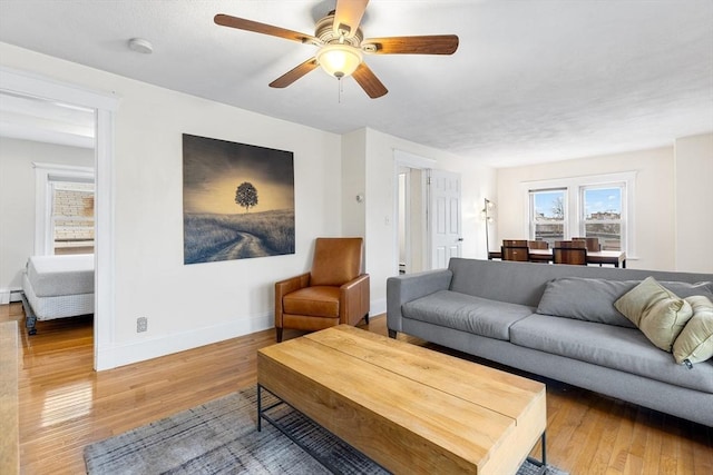 living room featuring baseboard heating, ceiling fan, and hardwood / wood-style flooring