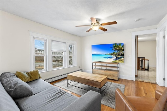 living room featuring baseboard heating, ceiling fan, and light hardwood / wood-style flooring