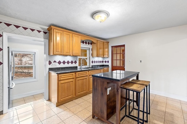 kitchen with light tile patterned flooring, a kitchen island, a breakfast bar area, and sink