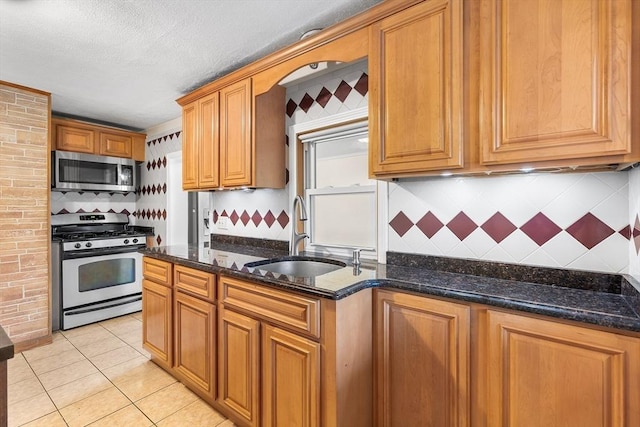 kitchen with backsplash, sink, stainless steel appliances, and dark stone counters