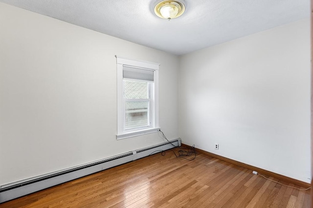 empty room featuring wood-type flooring and a baseboard radiator