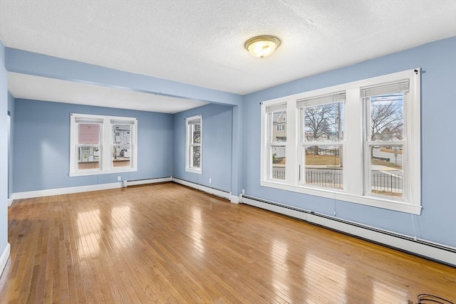 empty room featuring a textured ceiling, light wood-type flooring, and a baseboard radiator