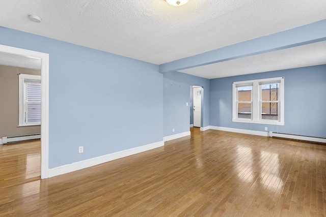 spare room with hardwood / wood-style floors, baseboard heating, and a textured ceiling