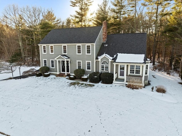 colonial home with a chimney and roof with shingles