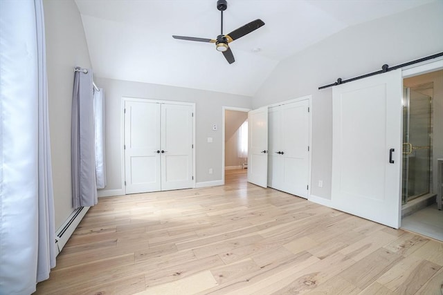 3 Woods Rd, Westminster, MA 01473 - unfurnished bedroom with a barn door, a baseboard radiator, light wood-style floors, vaulted ceiling, and multiple closets