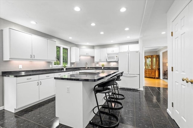 14 Vanessa Dr, Northborough, MA 01532 - kitchen with white appliances, granite tiled floors, dark countertops, a breakfast bar, and a kitchen island