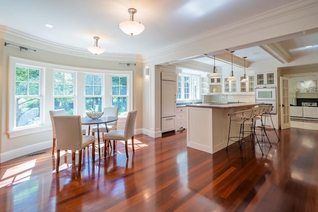 dining area featuring beam ceiling, ornamental molding, and dark hardwood / wood-style floors