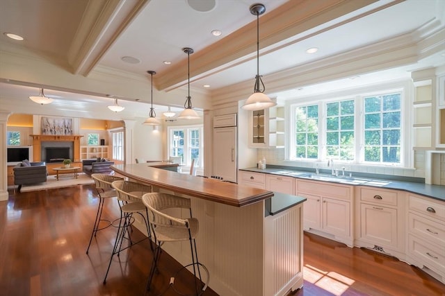 kitchen featuring a breakfast bar area, white cabinets, dark hardwood / wood-style flooring, hanging light fixtures, and beam ceiling