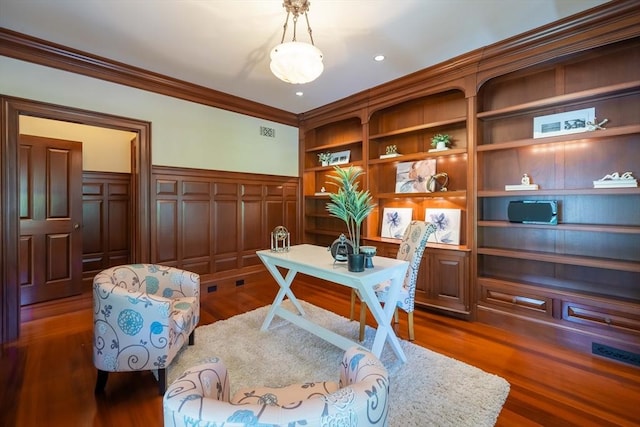 home office with built in shelves, ornamental molding, and dark hardwood / wood-style floors