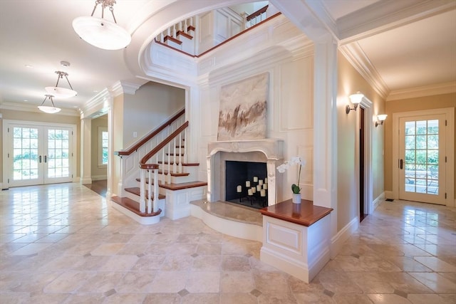 interior space featuring crown molding, a premium fireplace, french doors, and ornate columns