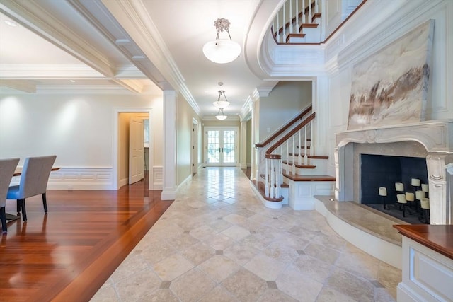 foyer entrance with a premium fireplace, wood-type flooring, ornamental molding, and french doors