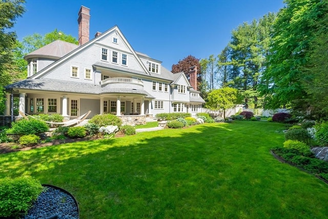 back of house featuring a balcony and a lawn