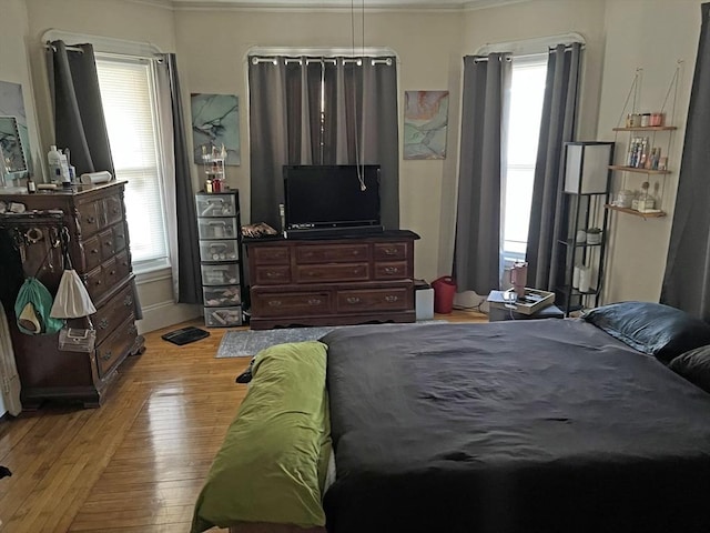 bedroom with wood finished floors and ornamental molding