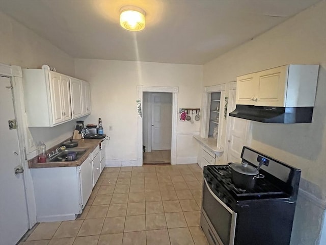 kitchen with ventilation hood, stainless steel range with gas cooktop, light tile patterned flooring, a sink, and white cabinets