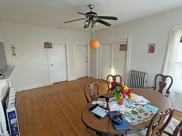 dining space with radiator, wood finished floors, baseboards, and ceiling fan