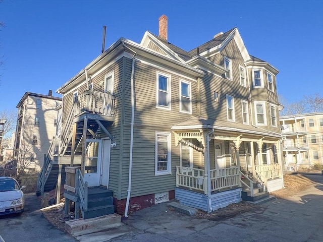 view of front of house featuring a balcony, covered porch, and a chimney