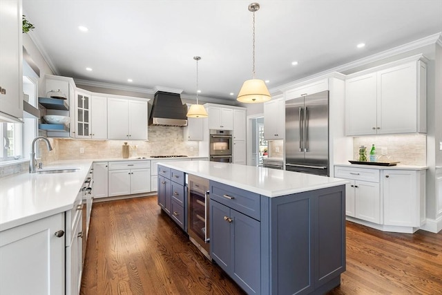 kitchen with beverage cooler, a sink, appliances with stainless steel finishes, a center island, and custom range hood