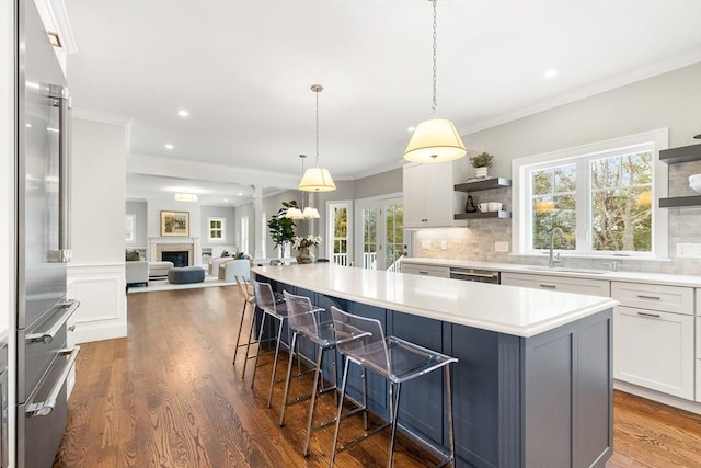 kitchen featuring dark wood-style flooring, a sink, a kitchen breakfast bar, open shelves, and crown molding