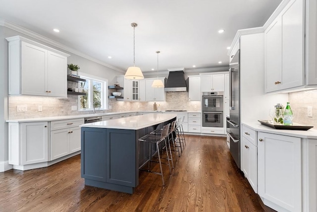 kitchen featuring stainless steel appliances, premium range hood, a breakfast bar, a center island, and open shelves