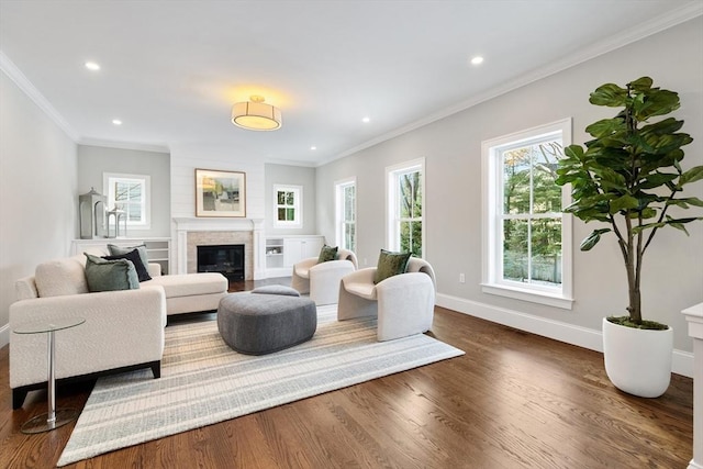 living room with ornamental molding, dark wood-type flooring, a glass covered fireplace, and baseboards