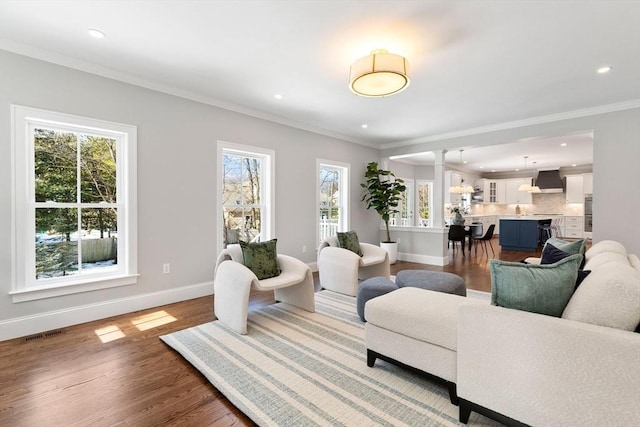 living room with baseboards, visible vents, wood finished floors, and ornamental molding