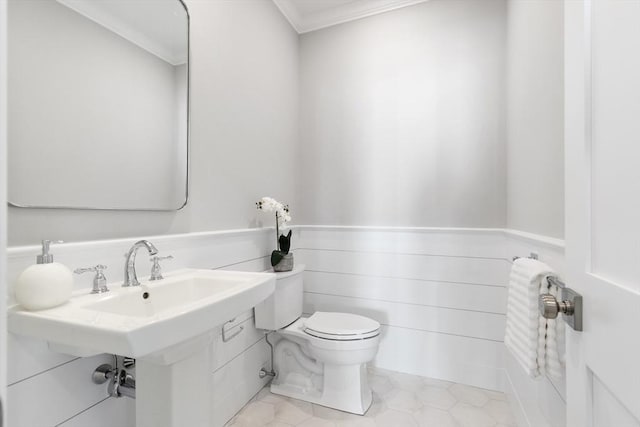 bathroom with wainscoting, crown molding, and toilet