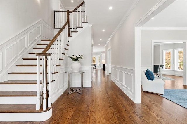 foyer entrance with stairway, a decorative wall, wood finished floors, and recessed lighting