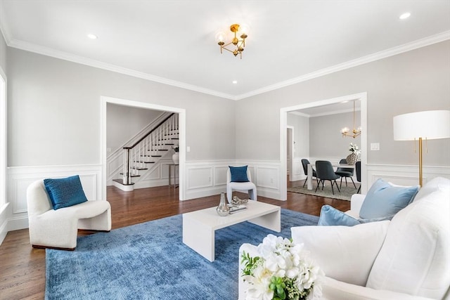 living room with ornamental molding, wood finished floors, a notable chandelier, and stairs