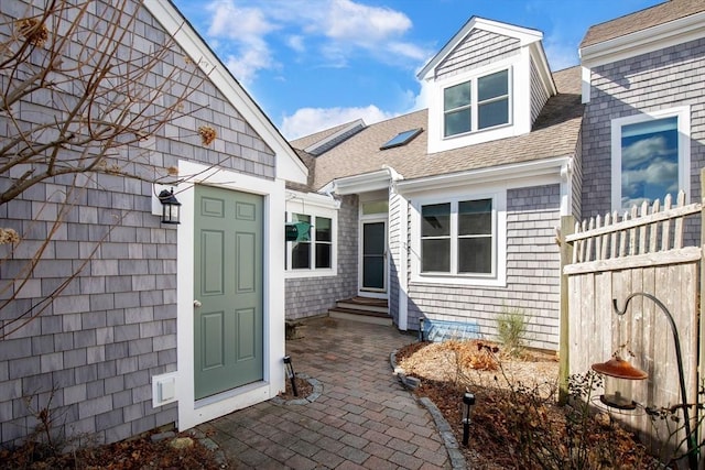 entrance to property with roof with shingles and fence